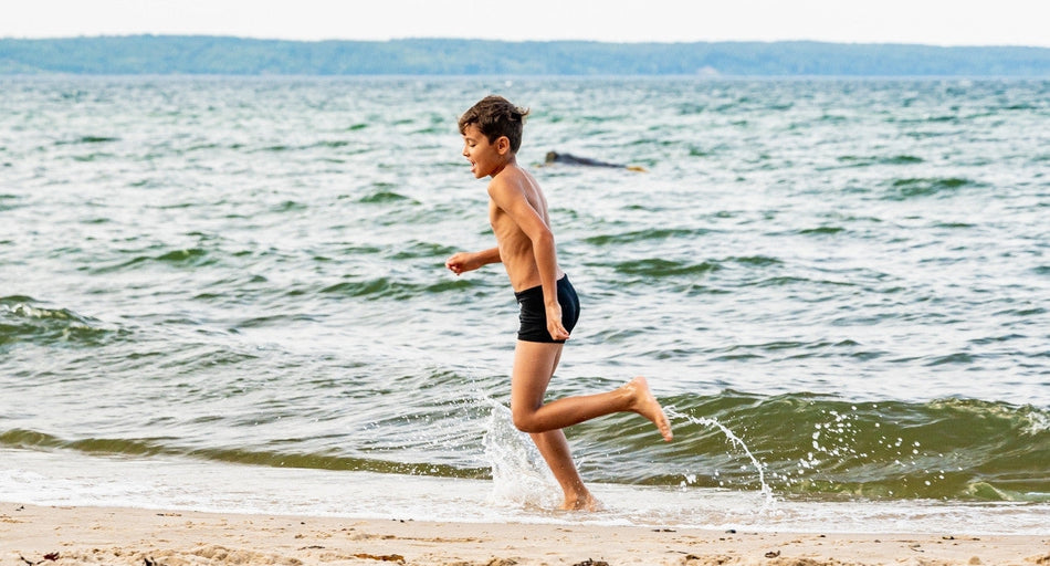 dreng løber i vandet på stranden