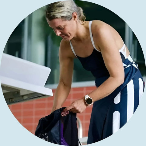 Kvinde i badedragt pakker svømmetaske.